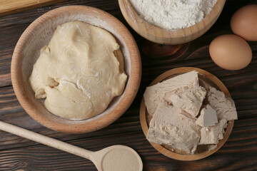 Different types of yeast, eggs, flour and dough on wooden table, flat lay