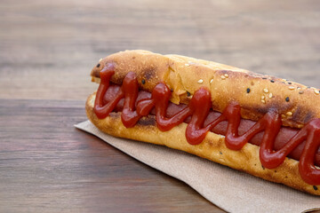 Fresh tasty hot dog with ketchup on wooden table, closeup