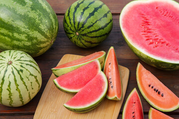 Different cut and whole ripe watermelons on wooden table, above view