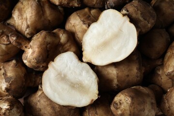 Whole and cut Jerusalem artichokes as background, top view