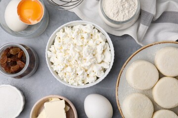 Uncooked cottage cheese pancakes and different ingredients on light grey table, flat lay