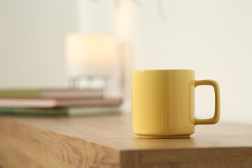 Yellow mug on wooden table indoors. Mockup for design