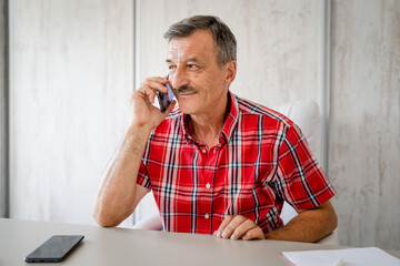 one man senior entrepreneur active caucasian male making a phone call talking while sitting at the desk table working at office manager and small business real people copy space