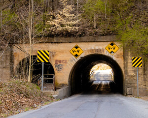 Single lane tunnel passing under railroad tracks. Service access to left. Including height restriction signs.
