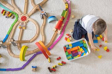 Preschool baby boy playing wooden Montessori materials rainbow arch railways at childish room. Top...