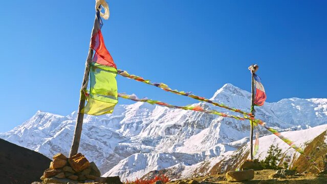 Slow motion of prayer flags blowing in the wind with majestic views of a snowy Annapurna Himalayan mountain, Nepal