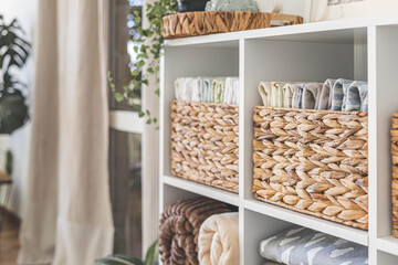 Neatly folded linen cupboard shelves storage at eco friendly straw basket placed closet organizer