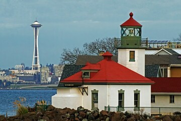 Fototapeta premium Alki Point Lighthouse by the sea with the background of the cityscape in Seattle, Washington, USA