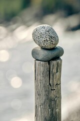 Vertical closeup shot of two stones stacked on an old wooden pole on an isolated background