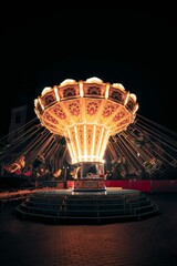 Low-angle of carousel with lights at night, dark background © Tim Sommer/Wirestock Creators