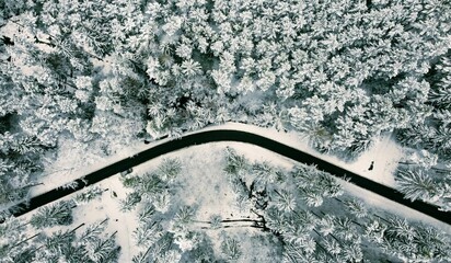 Aerial top view of a road through a snowy winter forest in Thruingia, Germany