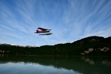 Red aircraft flying over the Big River Lake in Alaska