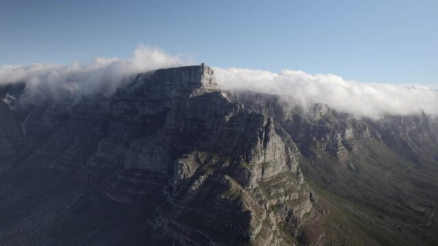 Drone footage of the Cape Town Signal hill cliff top reaching the clouds- with a blue sky background