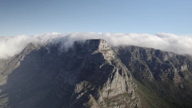 Drone footage of the Cape Town Signal hill cliff top reaching the clouds -with a blue sky background