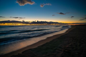 the sunset on the ocean at the beach with clouds and rocks