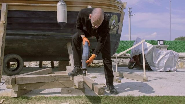 4K video of a man cutting timber with a reciprocating saw  in his garden