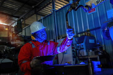 Engineer monitors and controls automatic welding robotic arm machine in intelligent automotive...