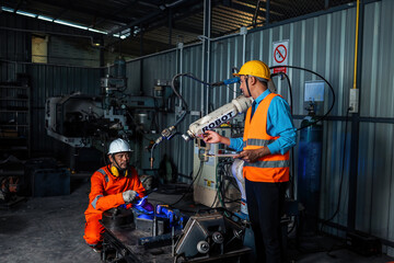 Engineer team service robot welding working in automation factory. People worker in safety suit work robotic arm software programming or replacing part in automated manufacturing industry technology