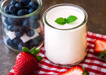 Homemade Yogurt, sour cream with blueberries and strawberries on stone slate background.