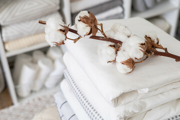 Cotton branch with pile of folded bed sheets and blankets