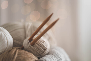 Cozy homely atmosphere. Female hobby knitting. Yarn in neutral shades in a soft basket of white and brown cord.
