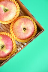 beautiful pink apple in the box on green background, healthy fruit