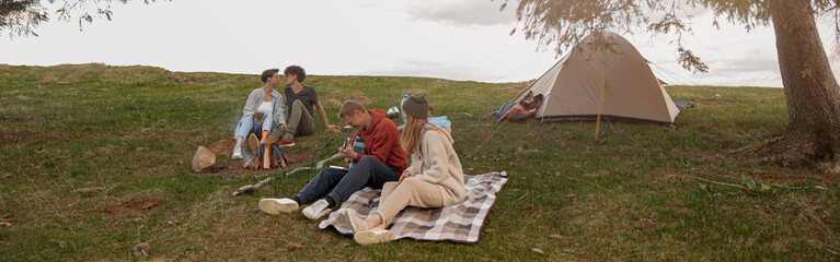 Two couples resting and having fun on top of mountain at tent. Camping concept.