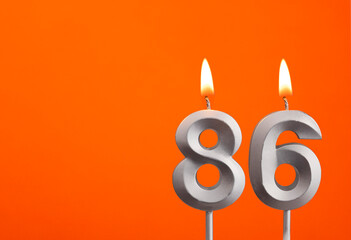 Number 86 - Silver Anniversary candle on orange background