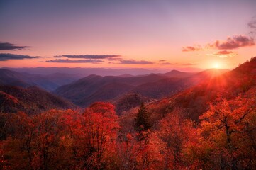 Scenic view of the sunset over an autumnal mountain forest under colorful dusk sky