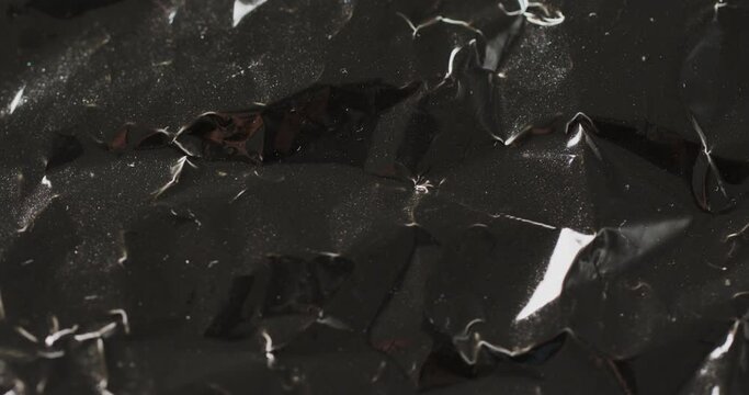 Close up of black crumpled plastic rubbish bag in slow motion