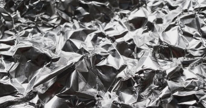 Close up of silver crumpled shiny aluminium in slow motion