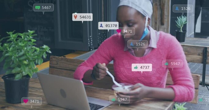 Animation of social media icons with numbers over african american woman using laptop