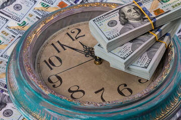 100 American dollar bills and the dial of a large wall clock