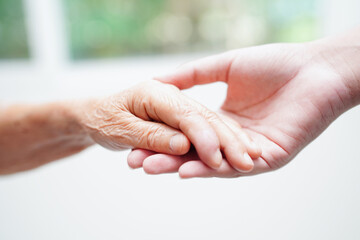 Asian young boy holding old grandmother woman hand together with love and care.