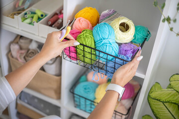Female hands placing basket with colored ball of yarn art crochet knitting ribbon cotton wool thread