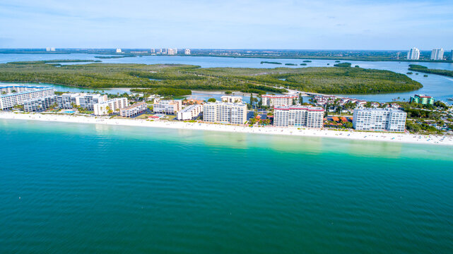Drones Eye View of Barefoot Beach in Bonita Springs, Florida Featuring Real Estate and White Sand Beach in the Foreground and Blue Bay Waters in the Background Surrounded by Mangroves