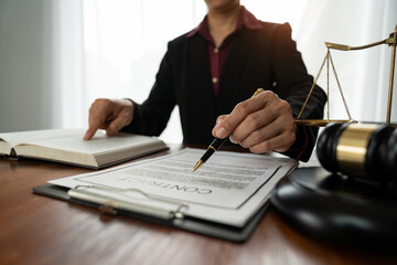Female lawyer or legal counsel sitting at desk reading and reviewing data in file folder, legal book in accordance with the principles of jurisprudence to study and find information.