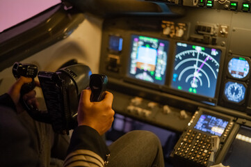 A man is studying to be a pilot in a flight simulator. Close-up of male hands navigating an aircraft.