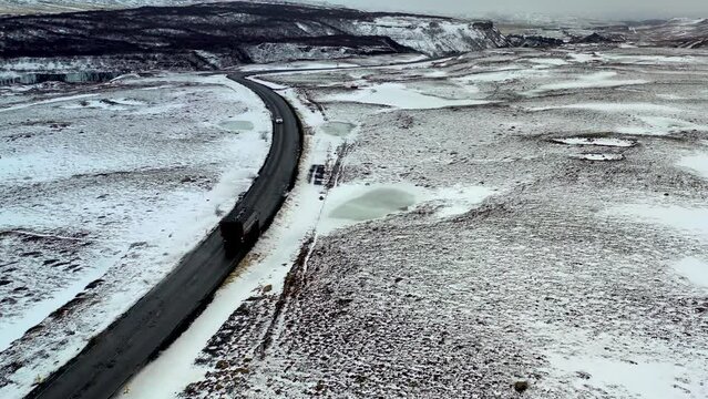 aerial view of a tourist bus in iceland driving along the road in the winter landscape.