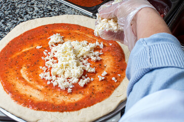 chef prepares pizza, puts mozzarella on dough