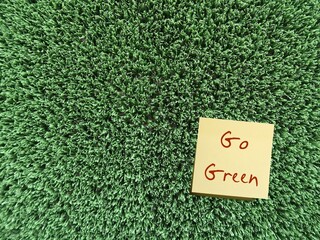 Green grass with handwritten text note GO GREEN means practices lead to more environmentally...