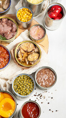 Canned vegetables, beans, fish and fruits in tin cans on a white background. Food stocks.