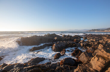 Surf washing over rocky central California coastline during golden hour at Cambria California United States