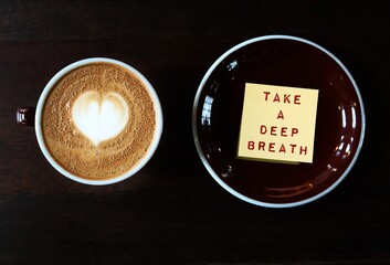 Coffee cup and note with handwritten text TAKE A DEEP BREATH, concept of to pause for a moment to...