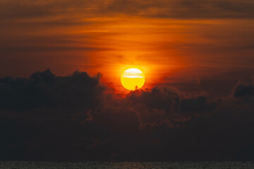 Sunset sky with clouds and bright orange sun in the evening.