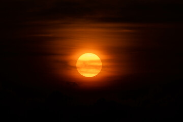 Sunset sky with clouds and bright orange sun in the evening.