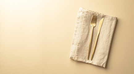 A linen napkin with a golden fork and a knife on it