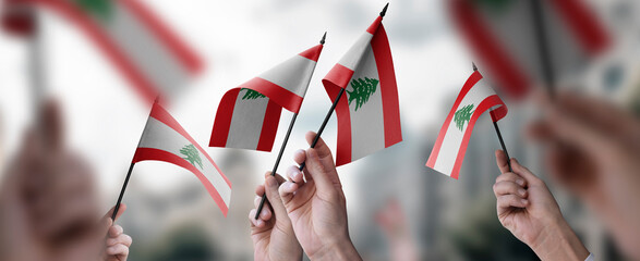 A group of people holding small flags of the Lebanon in their hands - obrazy, fototapety, plakaty