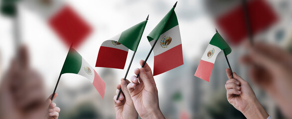 A group of people holding small flags of the Mexico in their hands