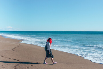 Girl with red hair walking on the beach turkey and looking into the distance